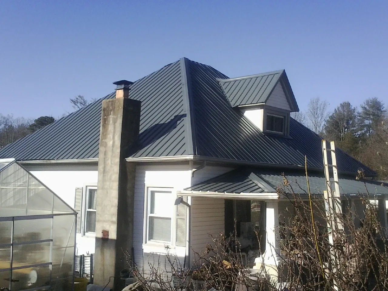 Dark blue standing seam metal roof on a white farmhouse with dormer — Slate & Tile Roof Repair by Roofing Brothers in Bailey Island