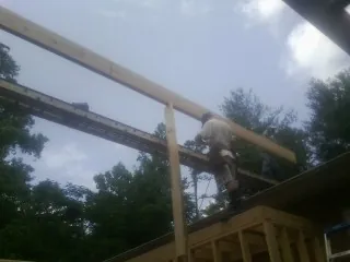 Carpenter setting a ridge beam over a new addition frame — Ice Dam Removal by Roofing Brothers in Bailey Island