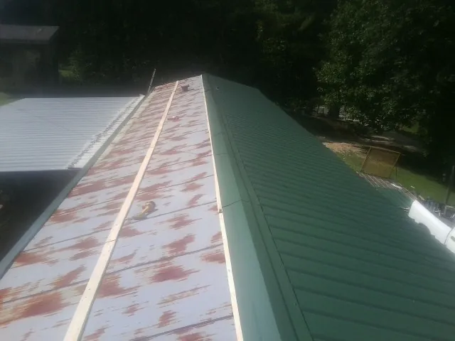 Old rusted panels beside newly installed green metal roofing — Wind Damage Roof Repair by Roofing Brothers in Bailey Island