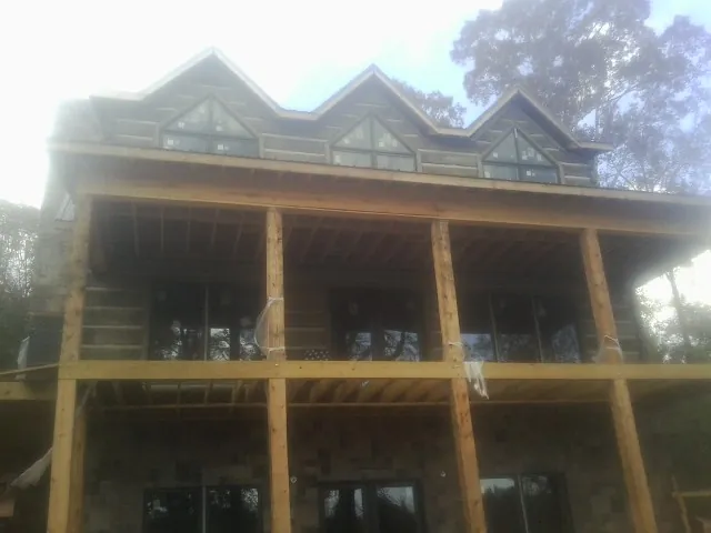 Dormers and porch framing on a large log home under construction — Roof Coating work by our crew in Bailey Island