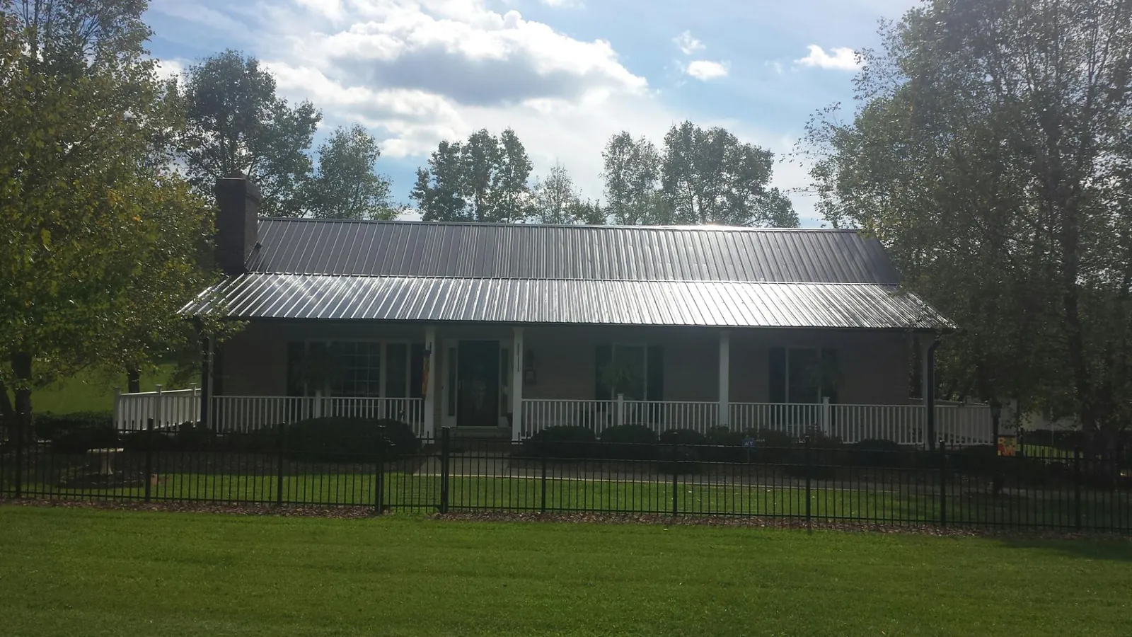 Gray metal roof on a brick ranch with a full width front porch — Gutter Guard Installation work by our crew in Bailey Island