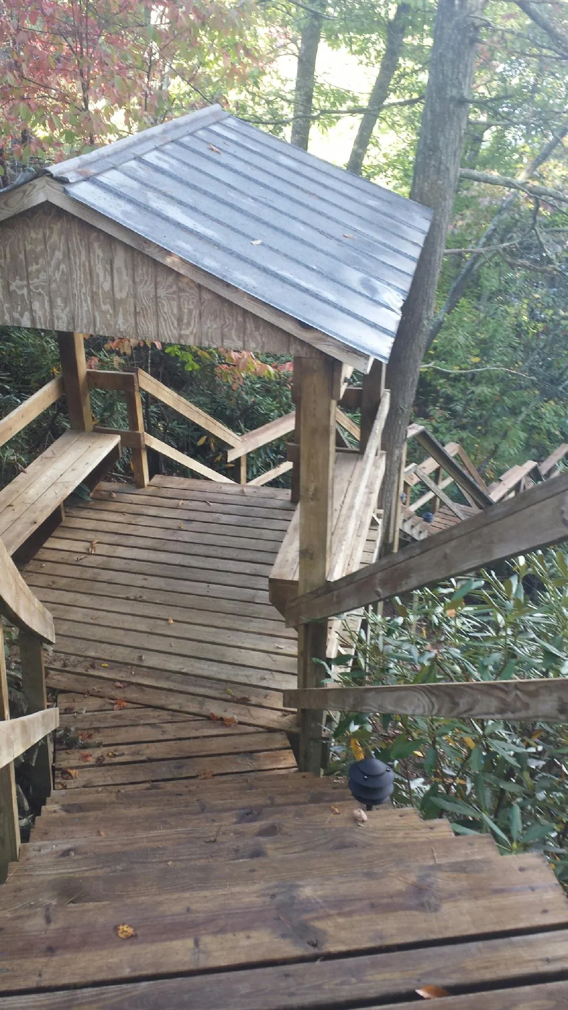 Metal roofed shelter over wooden steps on a wooded walkway — Skylight Repair & Installation work by our crew in Bailey Island