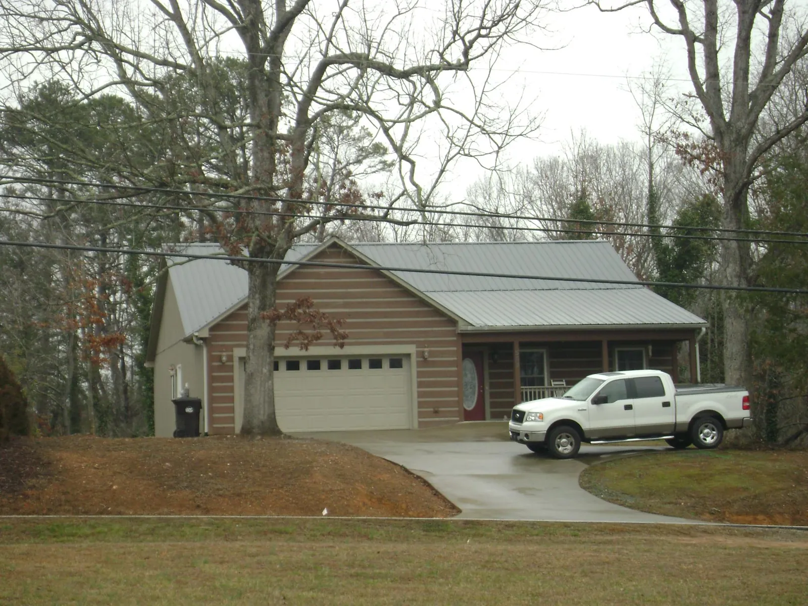 Gray metal roof on a log sided house with an attached two car garage in Bailey Island