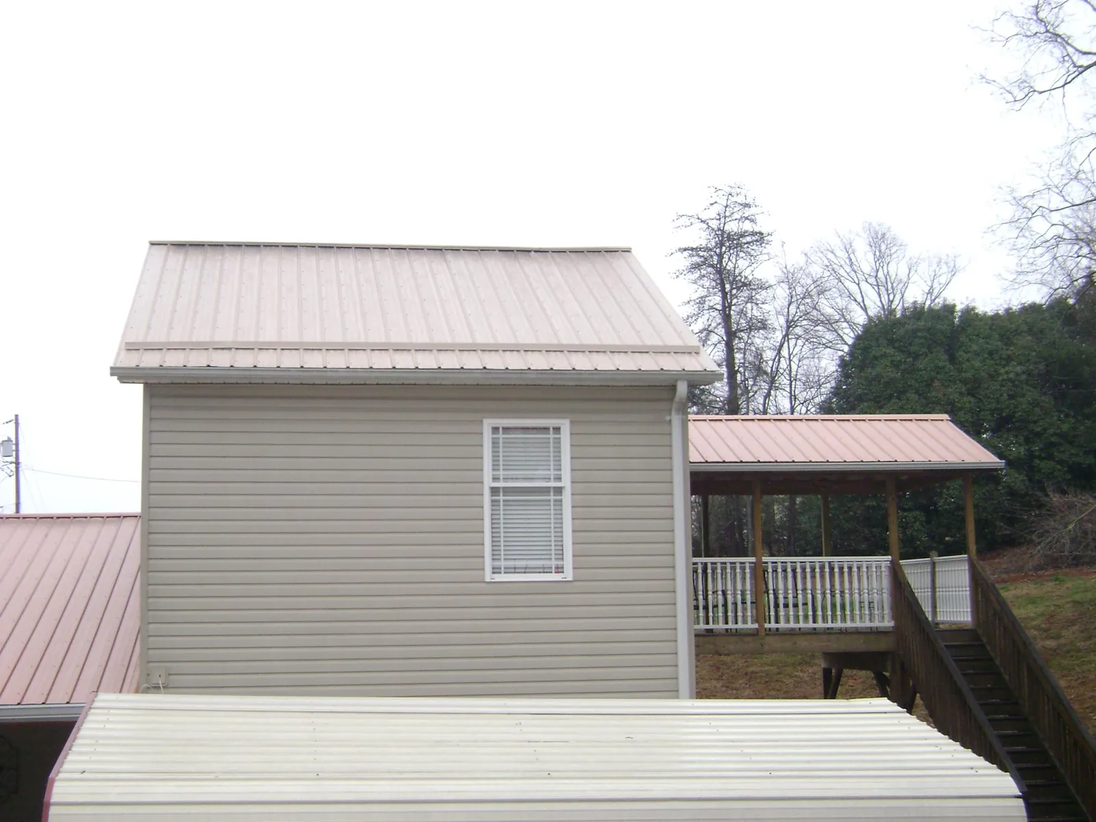 Tan metal roofs on a two story addition and attached porch, from a Roof Replacement job in Bailey Island