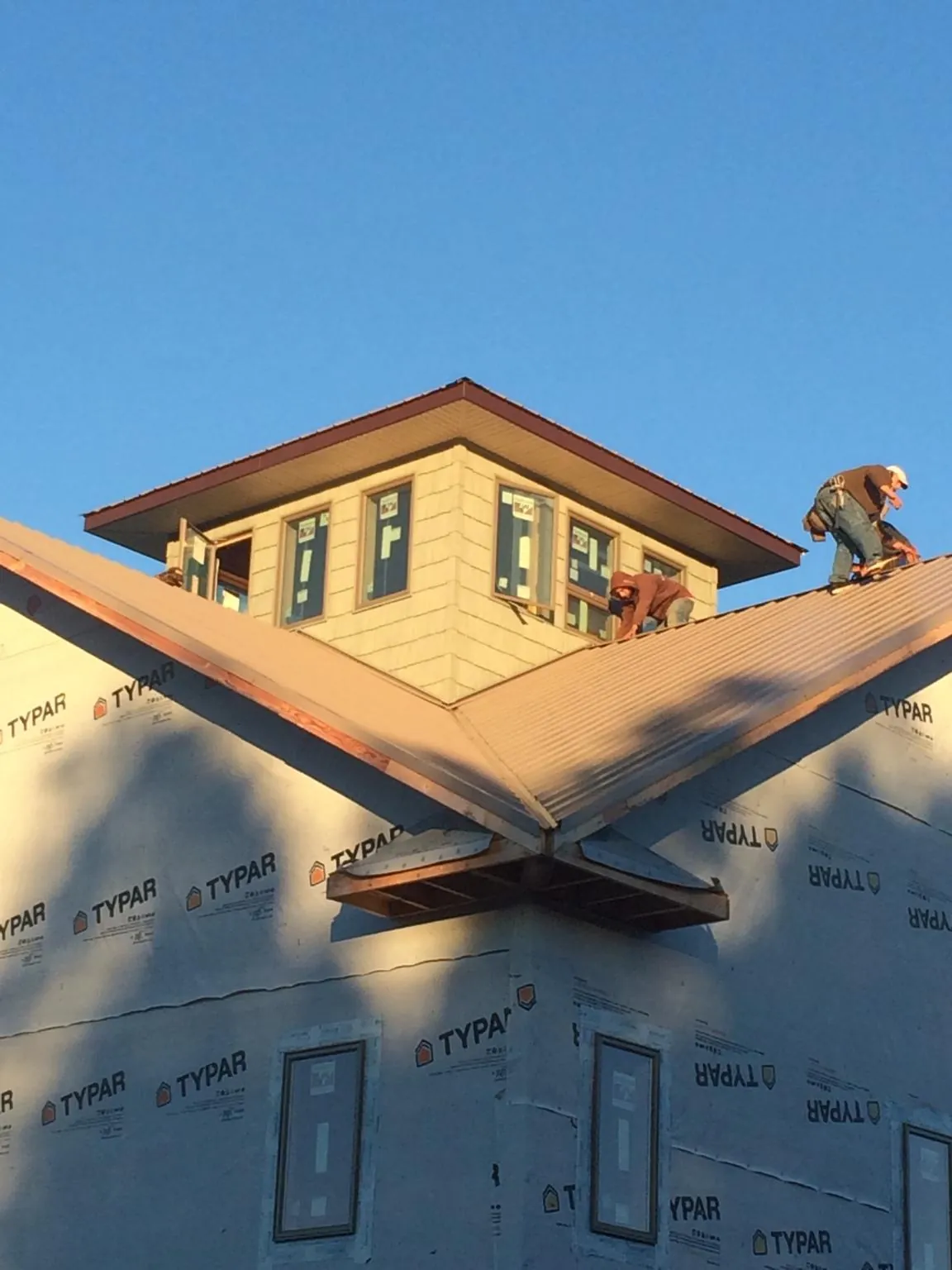 Roofers working around a rooftop cupola on a new metal roof at sunset — Roof Waterproofing in Bailey Island by Roofing Brothers